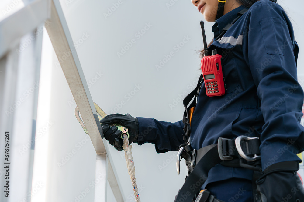 Fototapeta premium Asian woman Inspection engineer preparing and progress check of a wind turbine with safety in wind farm in Thailand.