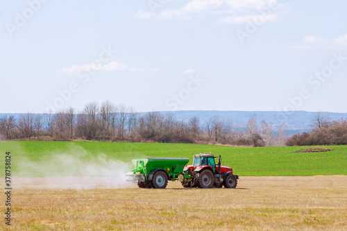 Tractor spreading fertilizer on grass field. Agricultural work. photo