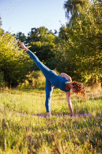 Beautiful young woman doing yoga asana pose during work out alone in summer