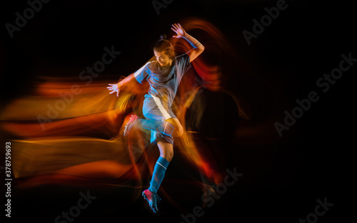 Motion. Football or soccer player on black studio background in mixed light. Young male sportive model training in action. Kicking ball, attacking, catching. Concept of sport, competition, winning. © master1305