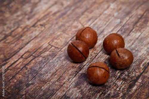 Whole macadamia nuts on table textured wooden background. Front and top view, close-up. Copyright space for website or logo
