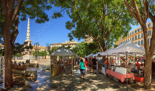 Malaga, Spain: summer market at Plaza de la Merced in the old town, on a cloudless day, with rows of market stalls and many visitors. photo