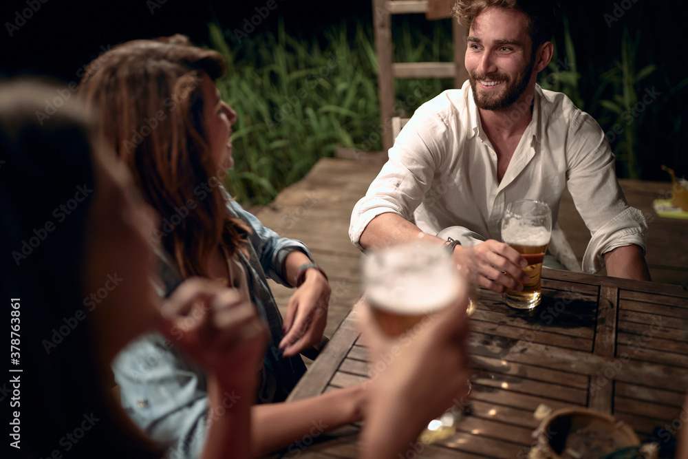 Fototapeta premium A man in girls company in the bar on the lake