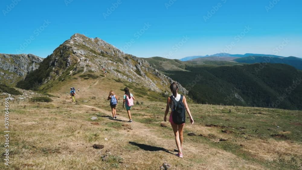 Group of young hikers with backpacks hiking on rocky mountain hills with beautiful view Group of young hikers with backpacks hiking on rocky mountain hills with beautiful view