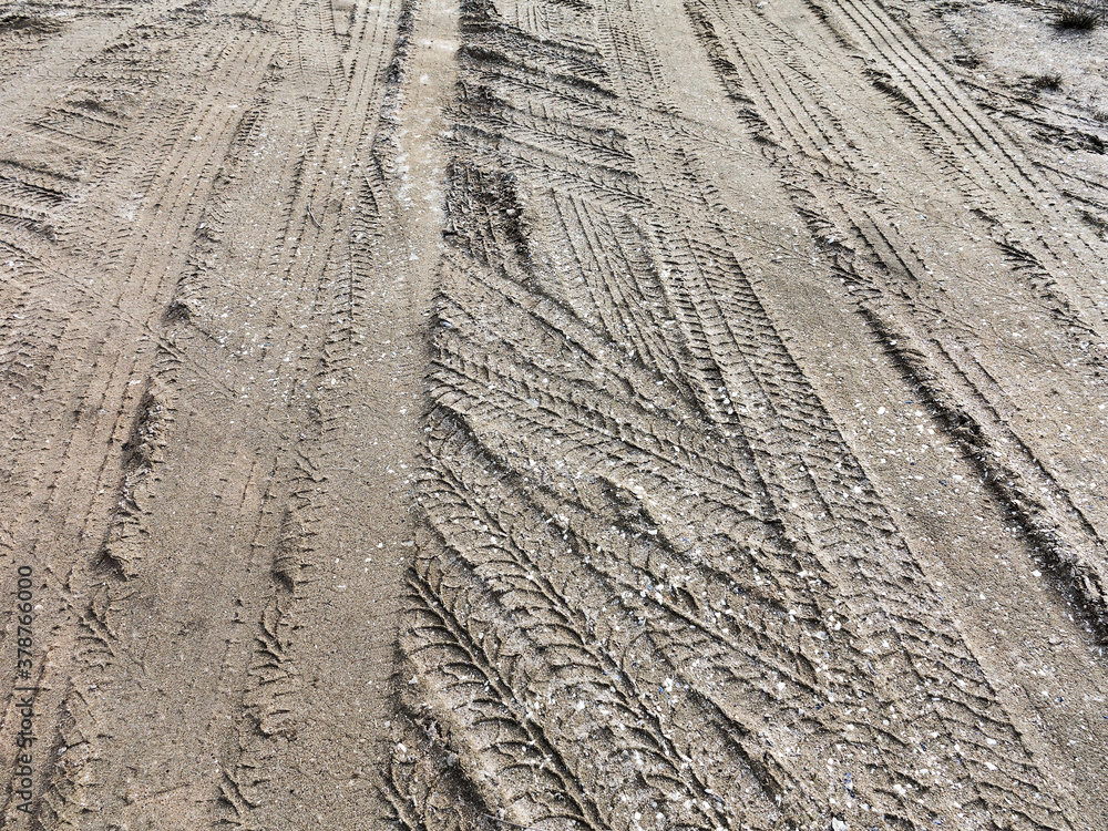 Tyre track and human footprint on sand texture background. Traces of off-road tires. Cracked earth on country road with traces of tires, cars, cracks and dirt. To use as background Tyre track and human footprint on sand texture background. Traces of off-road tires. Cracked earth on country road with traces of tires, cars, cracks and dirt. To use as background