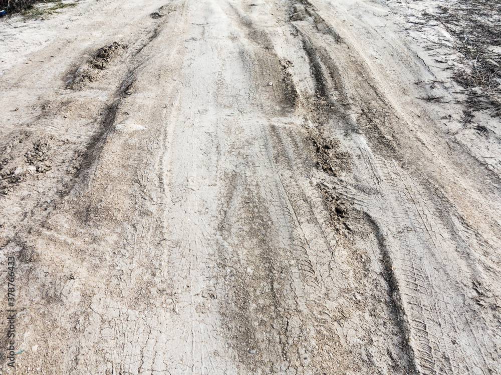 Tyre track and human footprint on sand texture background. Traces of off-road tires. Cracked earth on country road with traces of tires, cars, cracks and dirt. To use as background Tyre track and human footprint on sand texture background. Traces of off-road tires. Cracked earth on country road with traces of tires, cars, cracks and dirt. To use as background