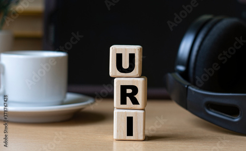 URI -acronum on cubes on the background of the tablet, headphones and a white cup photo