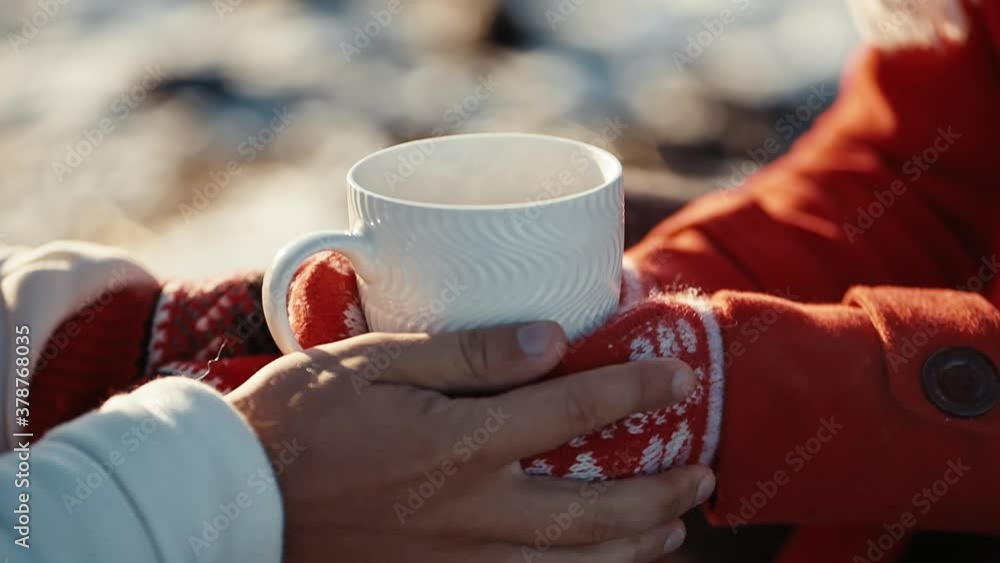 Close up hands of couple holding cups with hot tea at winter days. Coffee in the hands of a girl and a guy at xmas date. Freezing weather and warm hugs. Love concept. Close up hands of couple holding cups with hot tea at winter days. Coffee in the hands of a girl and a guy at xmas date. Freezing weather and warm hugs. Love concept.