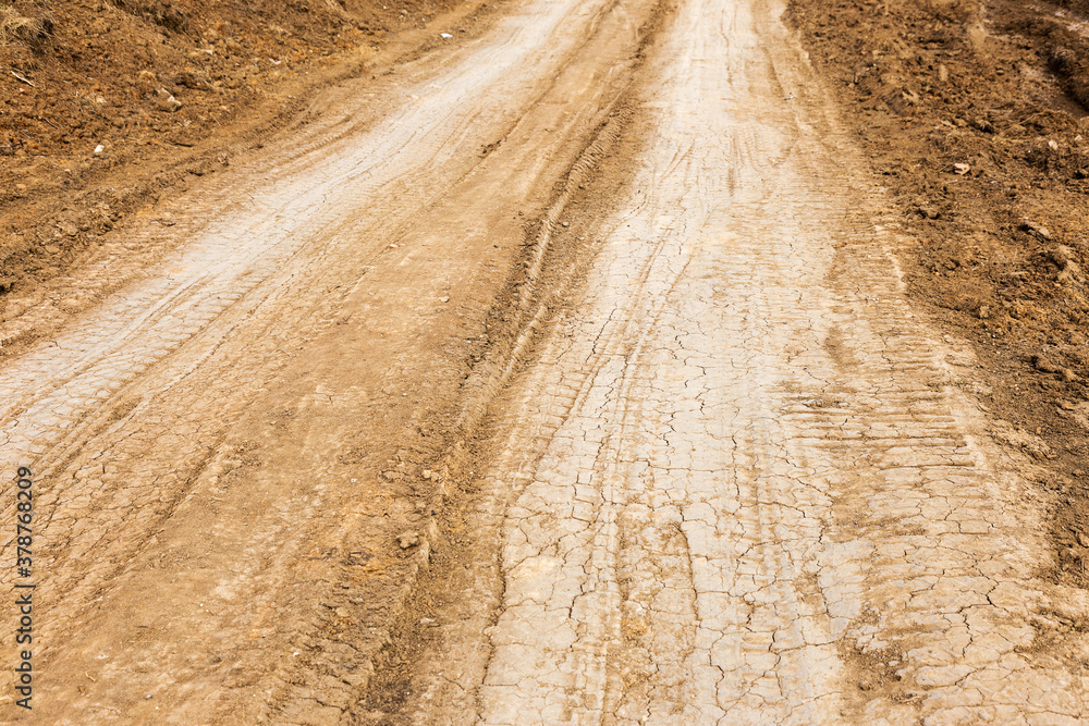 Tyre track and human footprint on sand texture background. Traces of off-road tires. Cracked earth on country road with traces of tires, cars, cracks and dirt. To use as background Tyre track and human footprint on sand texture background. Traces of off-road tires. Cracked earth on country road with traces of tires, cars, cracks and dirt. To use as background