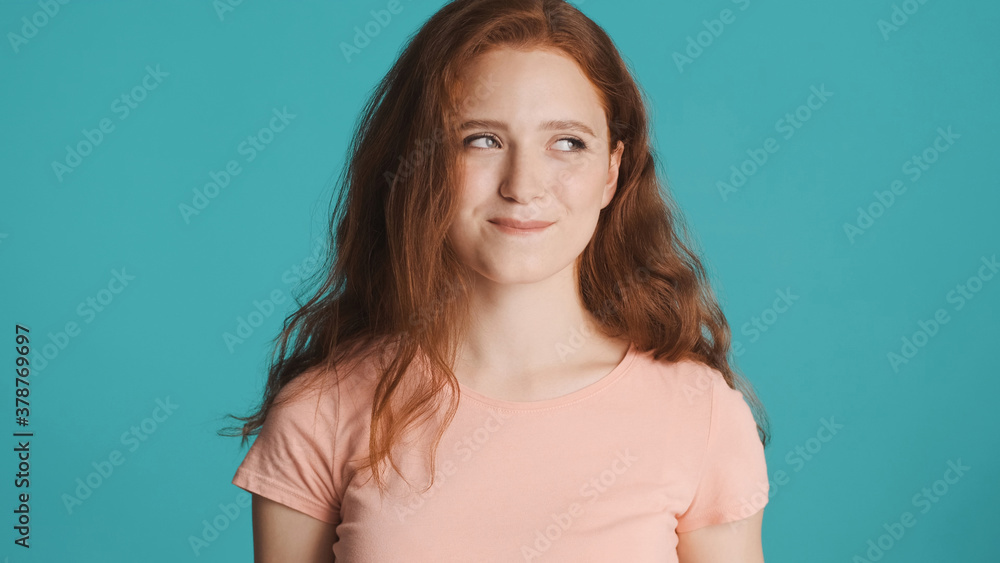 Portrait of cunning redhead girl slyly looking away over colorful background Portrait of cunning redhead girl slyly looking away over colorful background