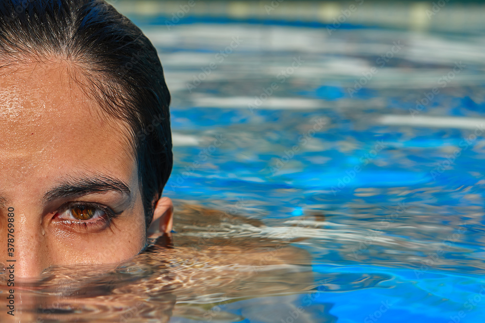 A beautiful girl in the pool taking a refreshing swim