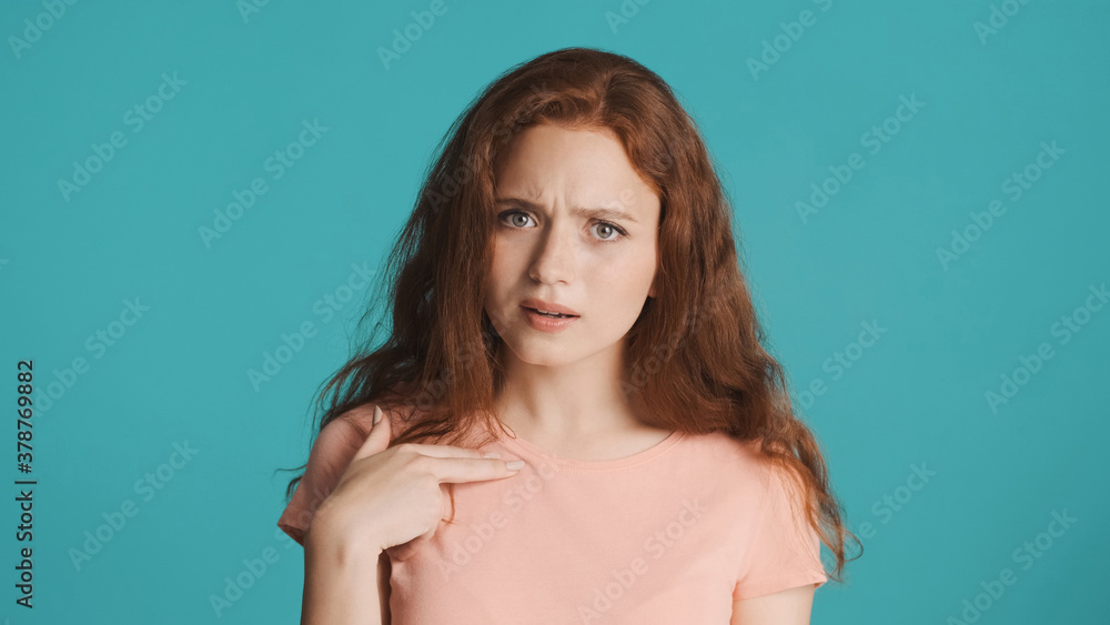 Confused girl pointing finger on herself and showing what expression on camera over colorful background Confused girl pointing finger on herself and showing what expression on camera over colorful background