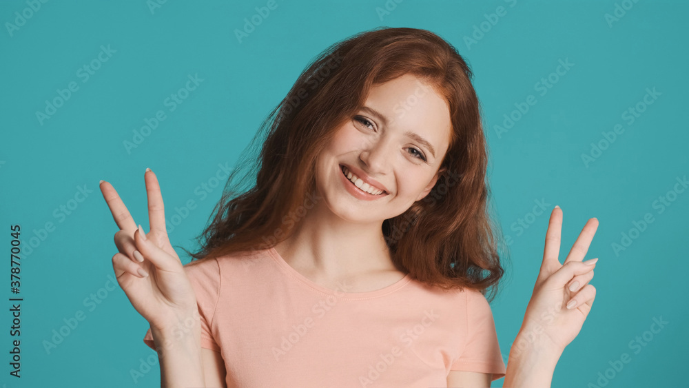 Pretty smiling woman joyfully showing peace gesture on camera over colorful background. Victory sign Pretty smiling woman joyfully showing peace gesture on camera over colorful background. Victory sign