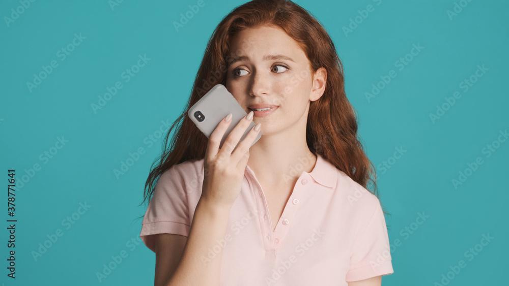 Attractive girl thoughtfully recording voice message on smartphone over colorful background Attractive girl thoughtfully recording voice message on smartphone over colorful background