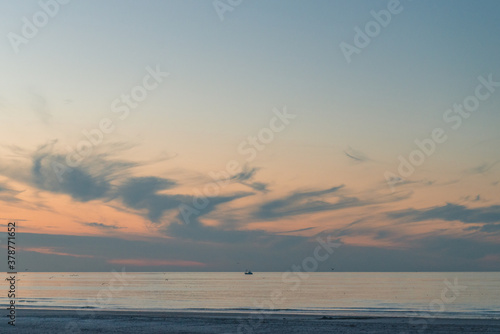 Fishing boat on the horizon on a ry sunset with some clouds on the beach of Ameland in the Netherland  idillic beautiful colors nature photo