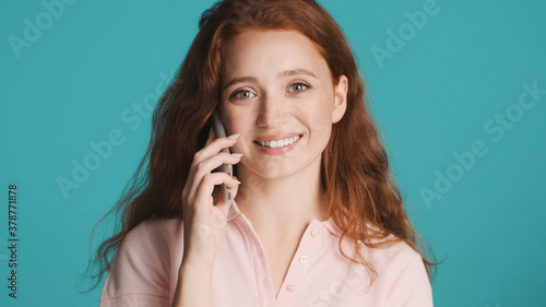 Beautiful smiling girl talking on phone happily looking in camera over colorful background