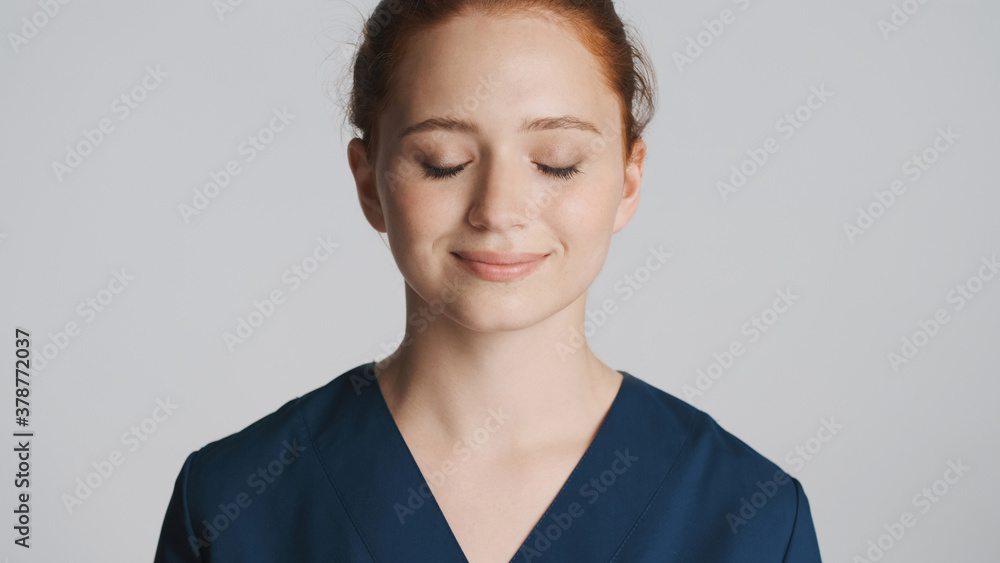 Portrait of pretty female doctor dreamily closing eyes on camera over white background Portrait of pretty female doctor dreamily closing eyes on camera over white background