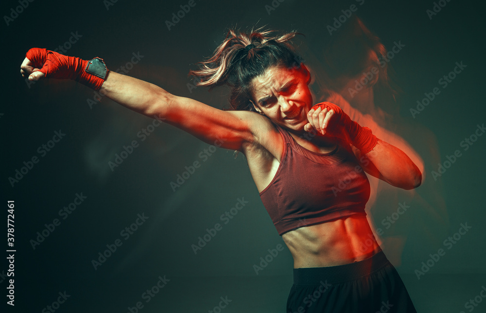 Cool girl fighter with relief abs makes jab in studio in neon light. Sport and motivation concept. Long exposure shot - obrazy, fototapety, plakaty 