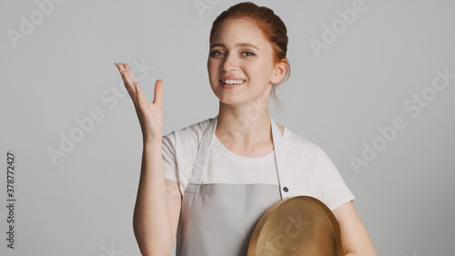 Photo Attractive waitress in apron with tray joyfully posing on camera over white back