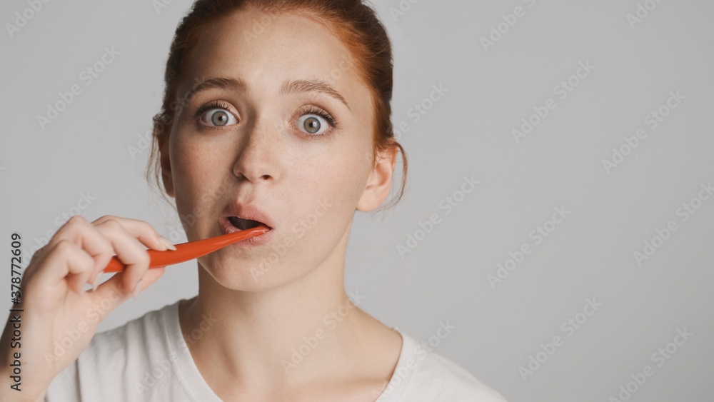 Portrait of attractive girl amazedly looking in camera brushing teeth over white background. Wow expression Portrait of attractive girl amazedly looking in camera brushing teeth over white background. Wow expression