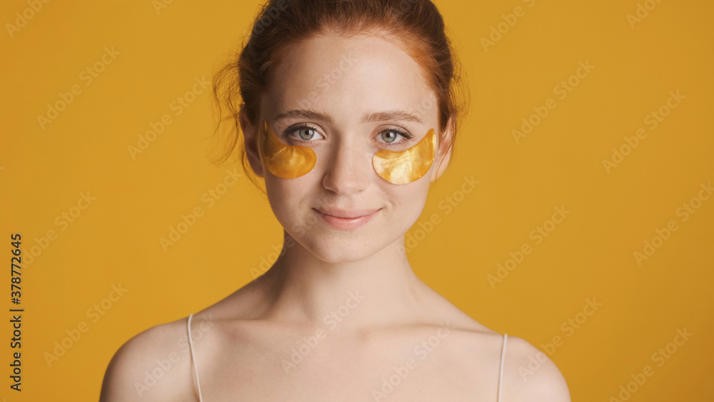 Beautiful smiling girl in eye patches intently looking in camera over colorful background. Beauty concept Beautiful smiling girl in eye patches intently looking in camera over colorful background. Beauty concept