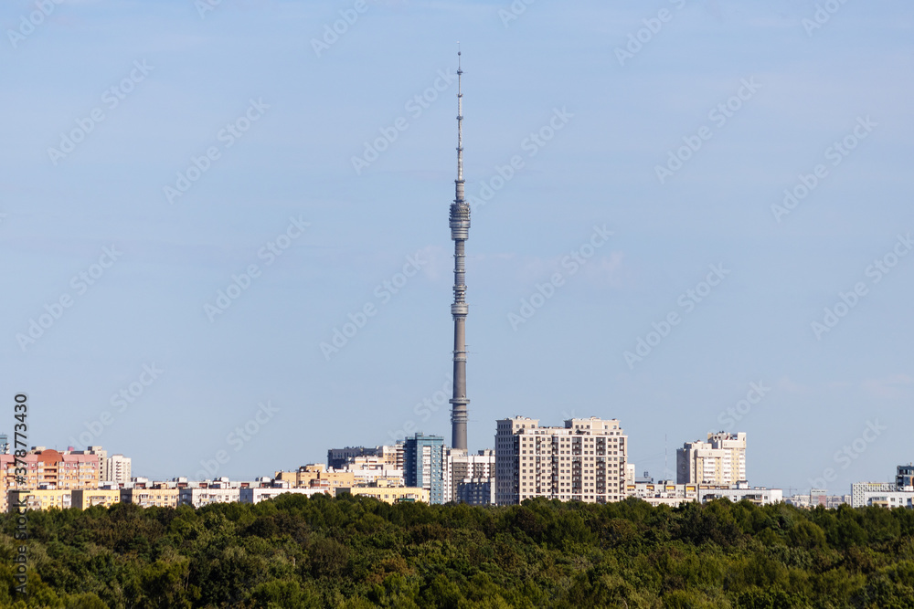 residential district with TV tower and lush green forest on horizon on sunny September day in Moscow city