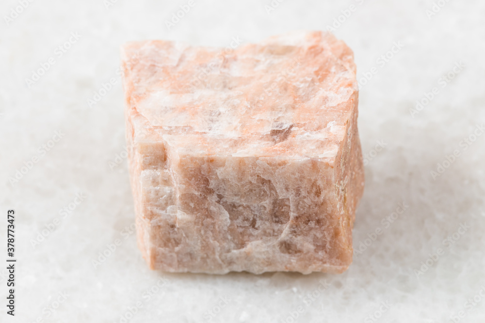 closeup of sample of natural mineral from geological collection - unpolished Feldspar rock on white marble background closeup of sample of natural mineral from geological collection - unpolished Feldspar rock on white marble background