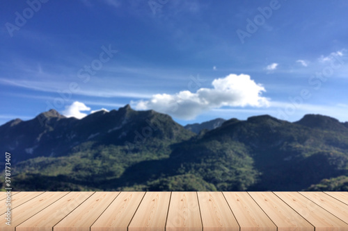 Empty wood plank table top with big green Mountian and clouds with blur background - For product display.