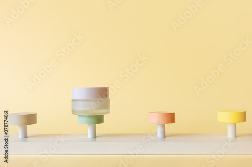 Mockup moisturizer cream in jar standing on pedestal on yellow background  front view. Skin care concept. Podium with moisturizer and empty spaces