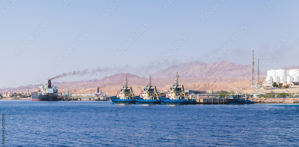 Tug boats and cargo ships are moored in Aqaba Port