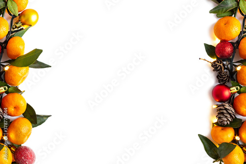 Christmas or New Year decoration background. Tangerines, Christmas decorations, garland and pine cones on white background. Christmas, winter, new year concept. Flat lay, top view, copy space.