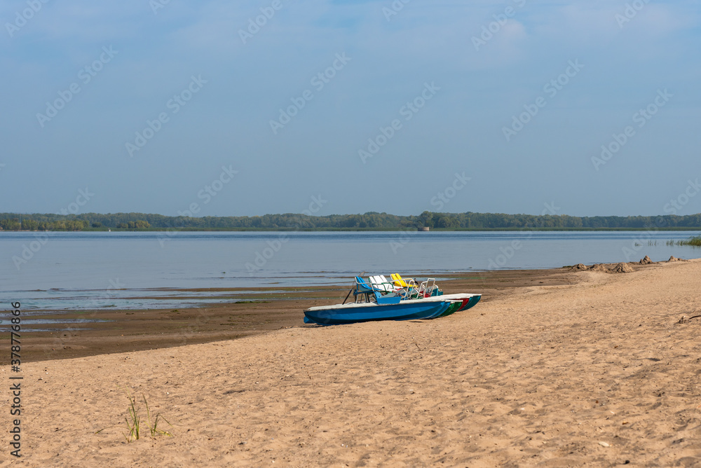 Pedalo rowing catamara stand on an empty sandy beach - pandemic, no people Pedalo rowing catamara stand on an empty sandy beach - pandemic, no people