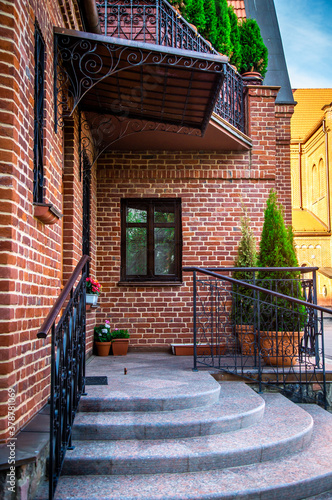 Fototapeta Naklejka Na Ścianę i Meble -  View of the beautiful facade of a red brick house. gray concrete steps to enter the house
