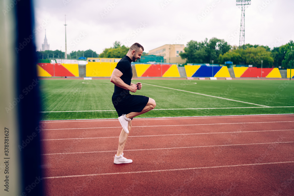 Side view of caucasian sportsman doing exercises for warming up muscles during morning workout, 20s male in active wear keeping healthy lifestyle losing weight and reaching perfect body shape