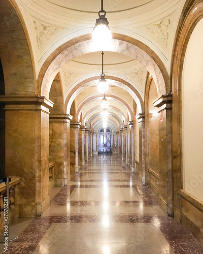 Hallway or corridor in historic public building with long aisles, archs and archways, wooden doors and ceiling lights photo