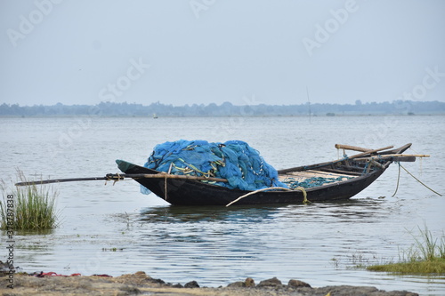 A single Fish catching small wooden boat on a river at the time of sunset in a remote village of India