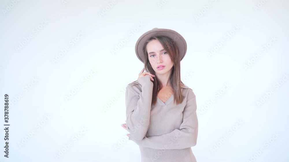 portrait of a young attractive fashion woman in a hat on a white background. Lady model isolated posing at camera in studio. Beauty in beige. The girl smiles and looks. Sexy with long hair and makeup portrait of a young attractive fashion woman in a hat on a white background. Lady model isolated posing at camera in studio. Beauty in beige. The girl smiles and looks. Sexy with long hair and makeup