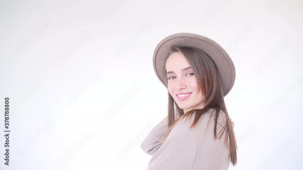 portrait of a young attractive fashion woman in a hat on a white background. Lady model isolated posing at camera in studio. Beauty in beige. The girl smiles and looks. Sexy with long hair and makeup portrait of a young attractive fashion woman in a hat on a white background. Lady model isolated posing at camera in studio. Beauty in beige. The girl smiles and looks. Sexy with long hair and makeup