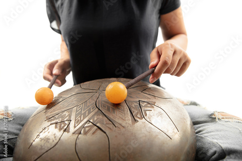 A close up of hands playing the hank drum on white studio background. Concept of hobby, professional occupation, music, traditions, festival. Copyspace for your ad. Ethnic instrument.