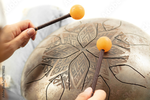 A close up of hands playing the hank drum on white studio background. Concept of hobby, professional occupation, music, traditions, festival. Copyspace for your ad. Ethnic instrument. photo