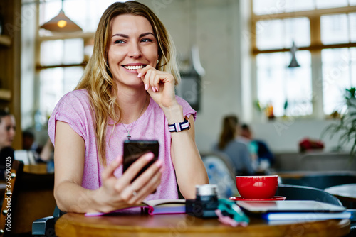 Cheerful woman using smartphone in cafe