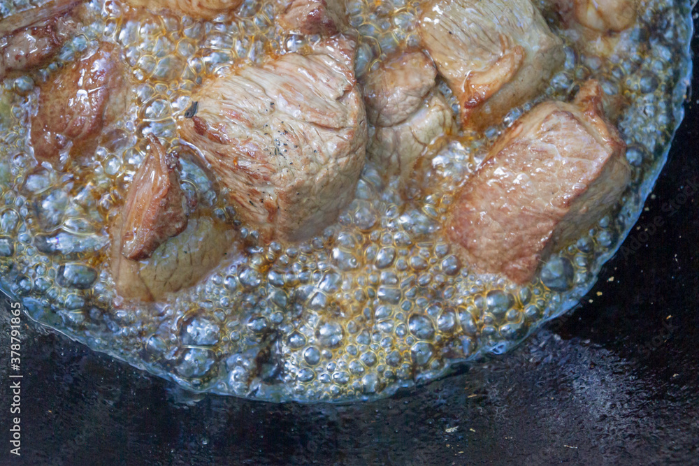 Cooking pilaf in a cauldron on the grill outside in the summer Cooking pilaf in a cauldron on the grill outside in the summer