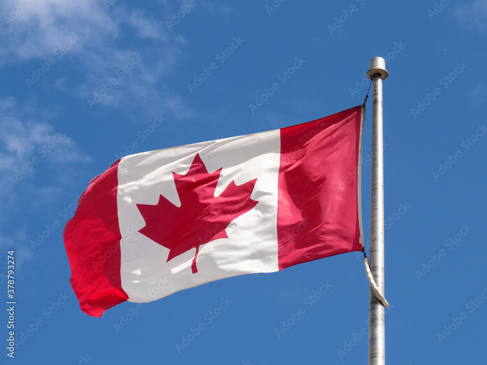 a Canada flag on a blue sky seen with the flagpole on the right a Canada flag on a blue sky seen with the flagpole on the right
