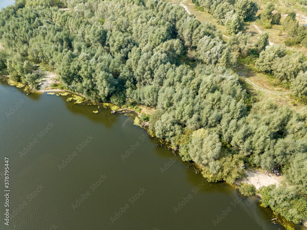 Green banks of a country river. Aerial drone view, sunny summer day.