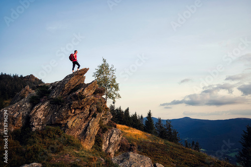 Junge, sportliche Frau steht am Gipfel und genießt den Sonnenuntergang am Osser