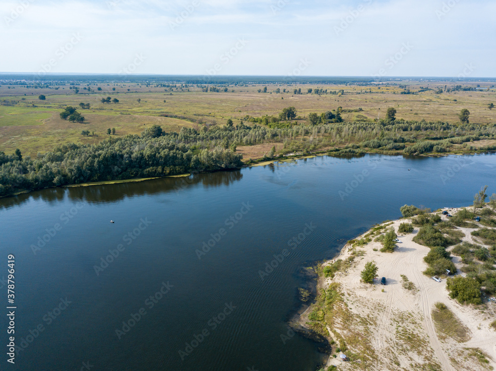 Aerial drone view. The bend of a wide river among green meadows. Sunny summer day. Aerial drone view. The bend of a wide river among green meadows. Sunny summer day.