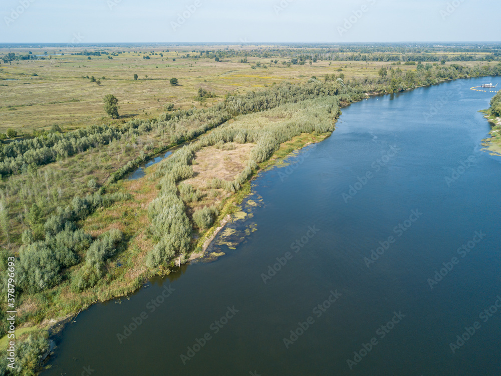 Aerial drone view. The bend of a wide river among green meadows. Sunny summer day. Aerial drone view. The bend of a wide river among green meadows. Sunny summer day.