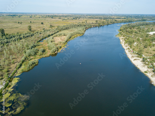 Aerial drone view. The bend of a wide river among green meadows. Sunny summer day.