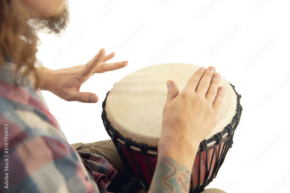 Fotka „Man plays ethnic drum darbuka percussion, close up musician isolated  on white studio background. Male hands tapping djembe, bongo in rhythm.  Musical handmade instruments, world culture sound.“ ze služby Stock