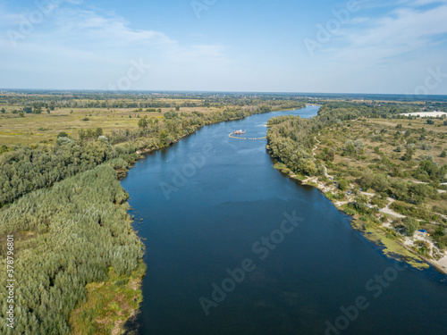 Aerial drone view. The bend of a wide river among green meadows. Sunny summer day.